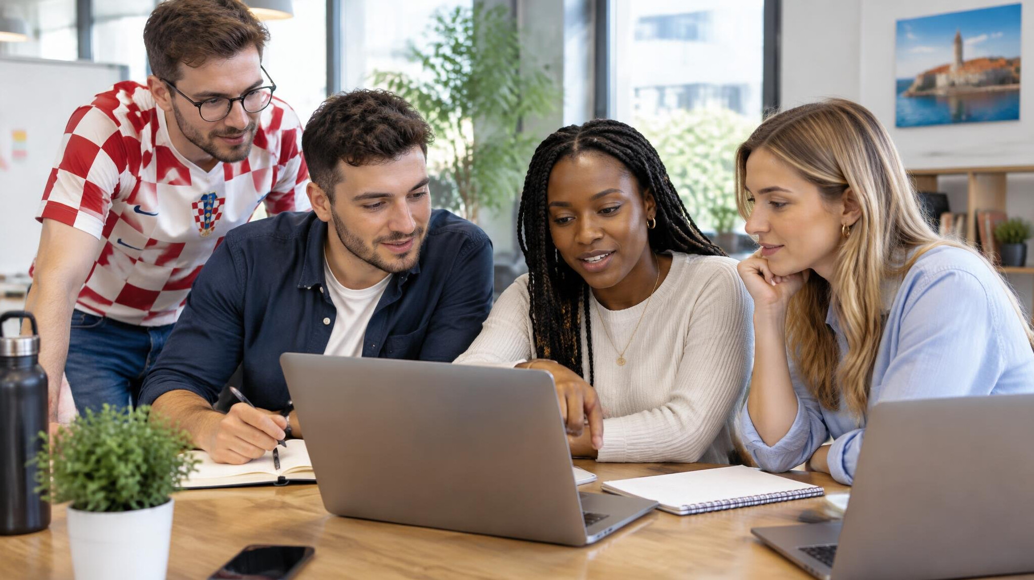 Diverse group of young professionals discussing programming topics around a table with laptops